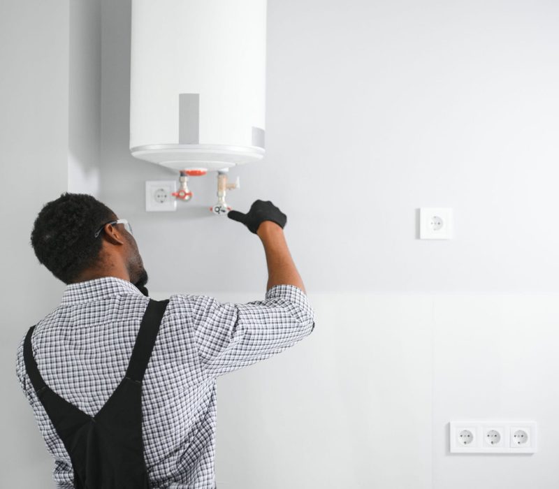 African american worker set up gas heating boiler at home.
